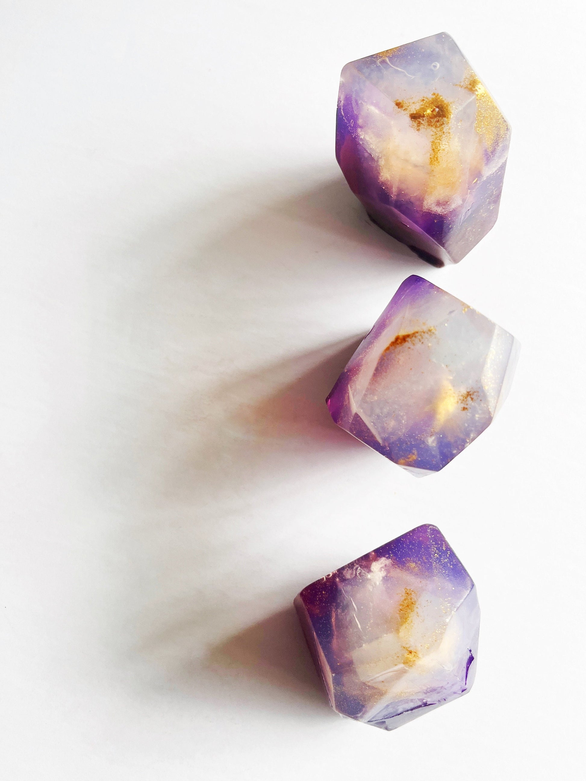 Three purple with gold sparkle gem shaped soaps on a white background
