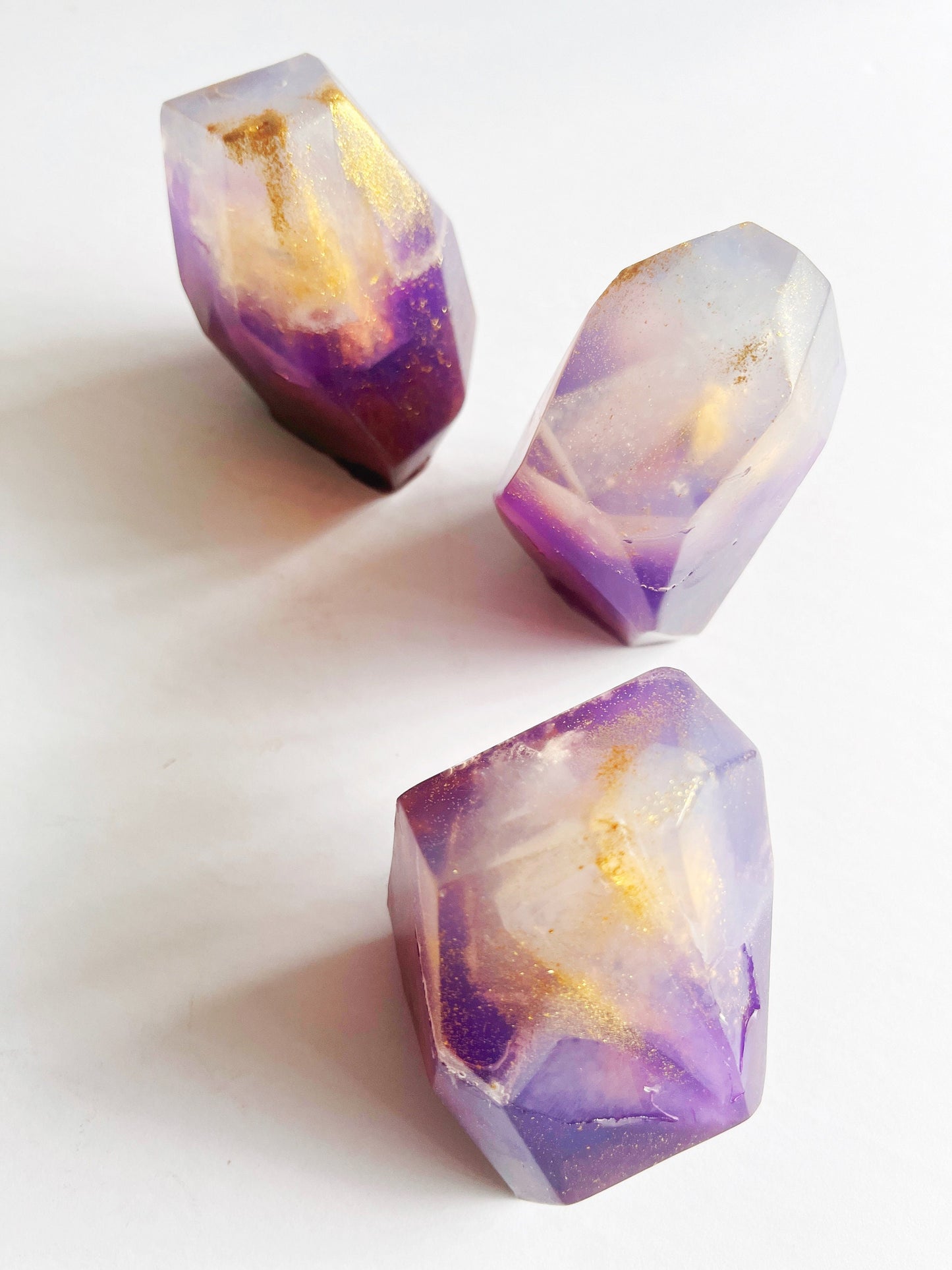 Three purple and gold gem shaped soaps on a white background