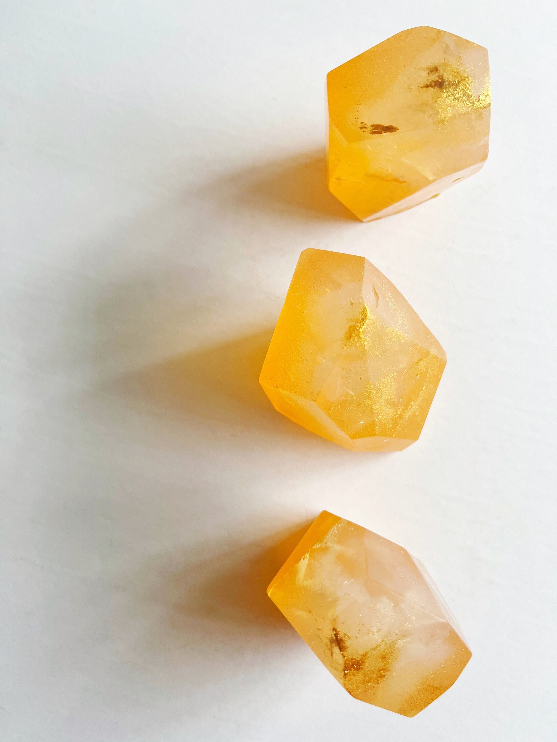 Three orange gem shaped soaps on a white background.