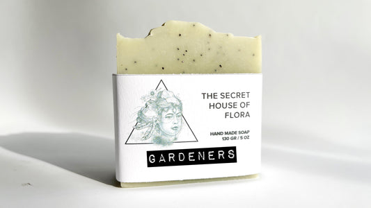 Bar of soap light green soap with poppy seeds sprinkled throughout, with a label on a white background.