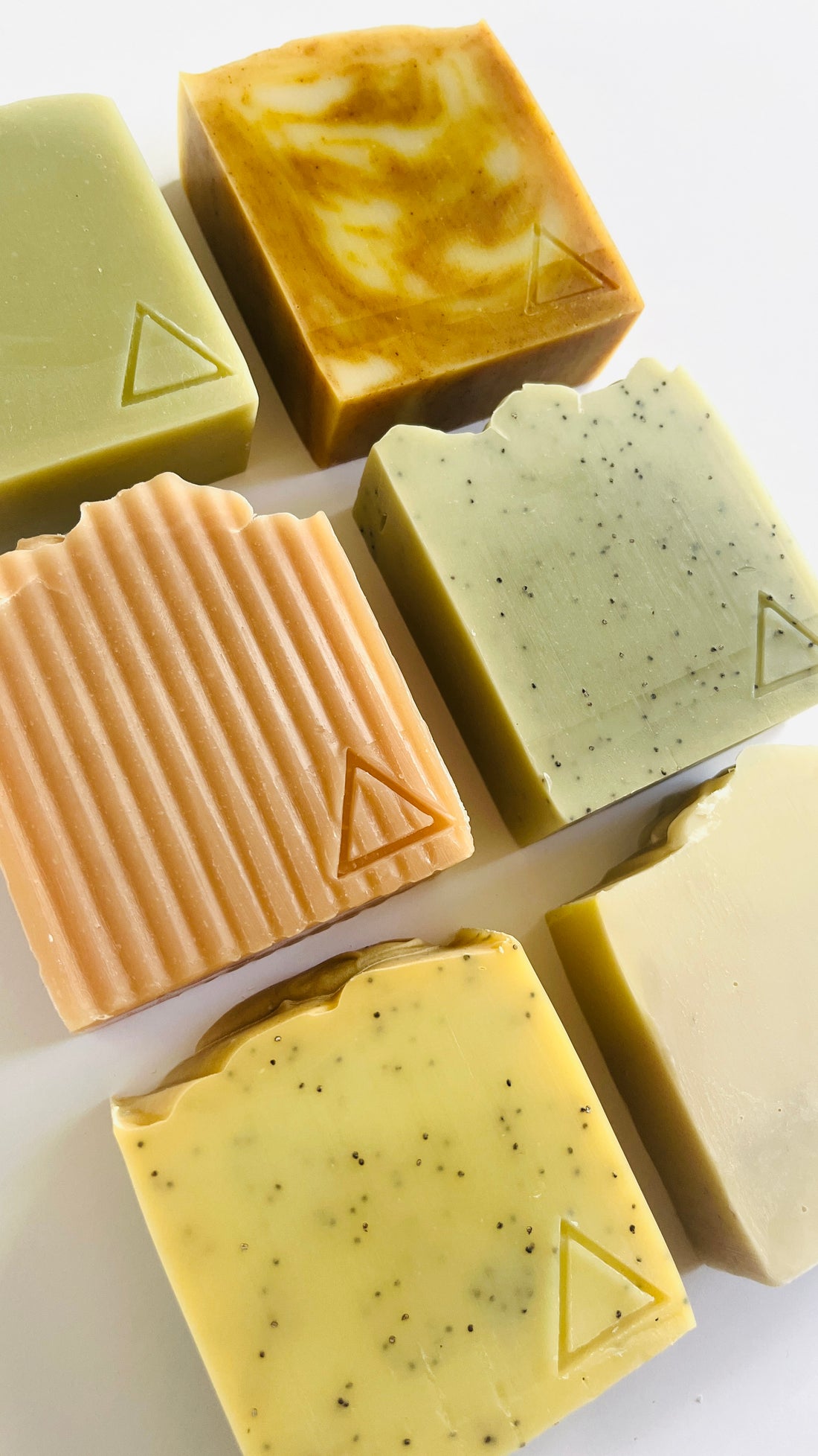 6 different bars of soap with unique textures and colors on a light background