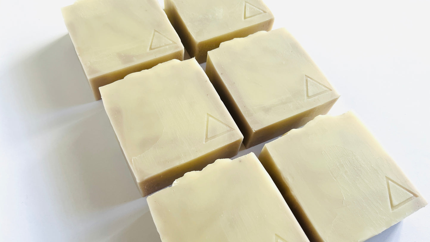 Six square soap bars with a triangle logo on a white background