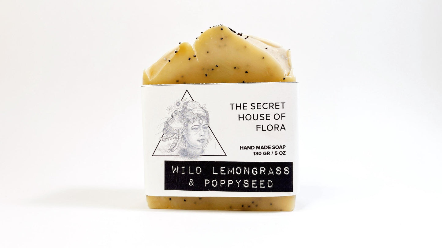 Bar of light yellow soap with poppy seeds sprinkled throughout with 'The Secret House of Flora' label on a white background