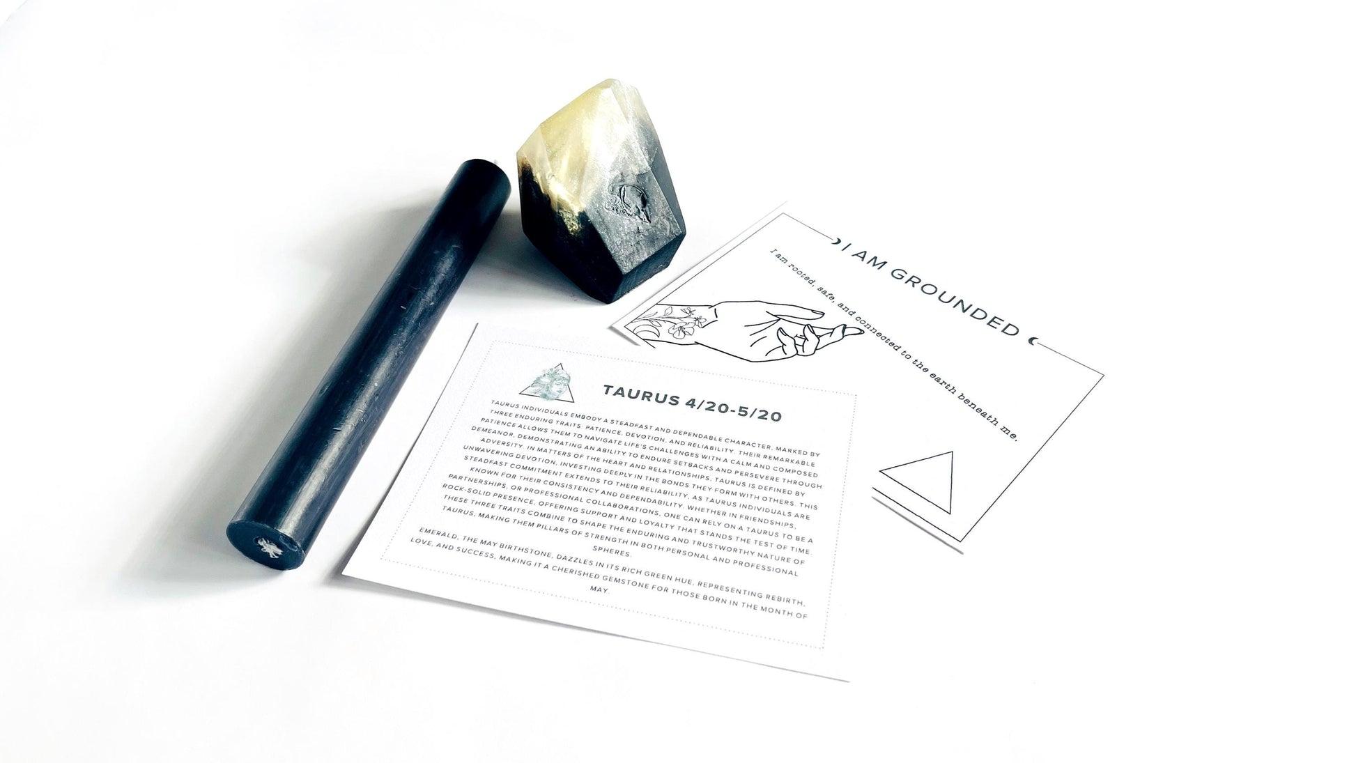 Smoky black crystal gem shaped soap, black taper candle, and affirmation cards on a white background