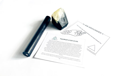 Smoky black crystal gem shaped soap, black taper candle, and affirmation cards on a white background
