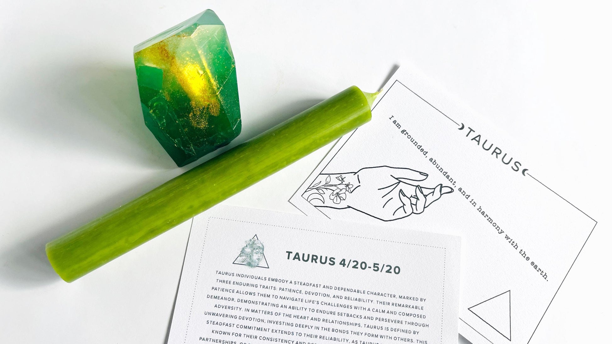 Green taper candle and  gem shaped soap with Taurus zodiac cards on a white background