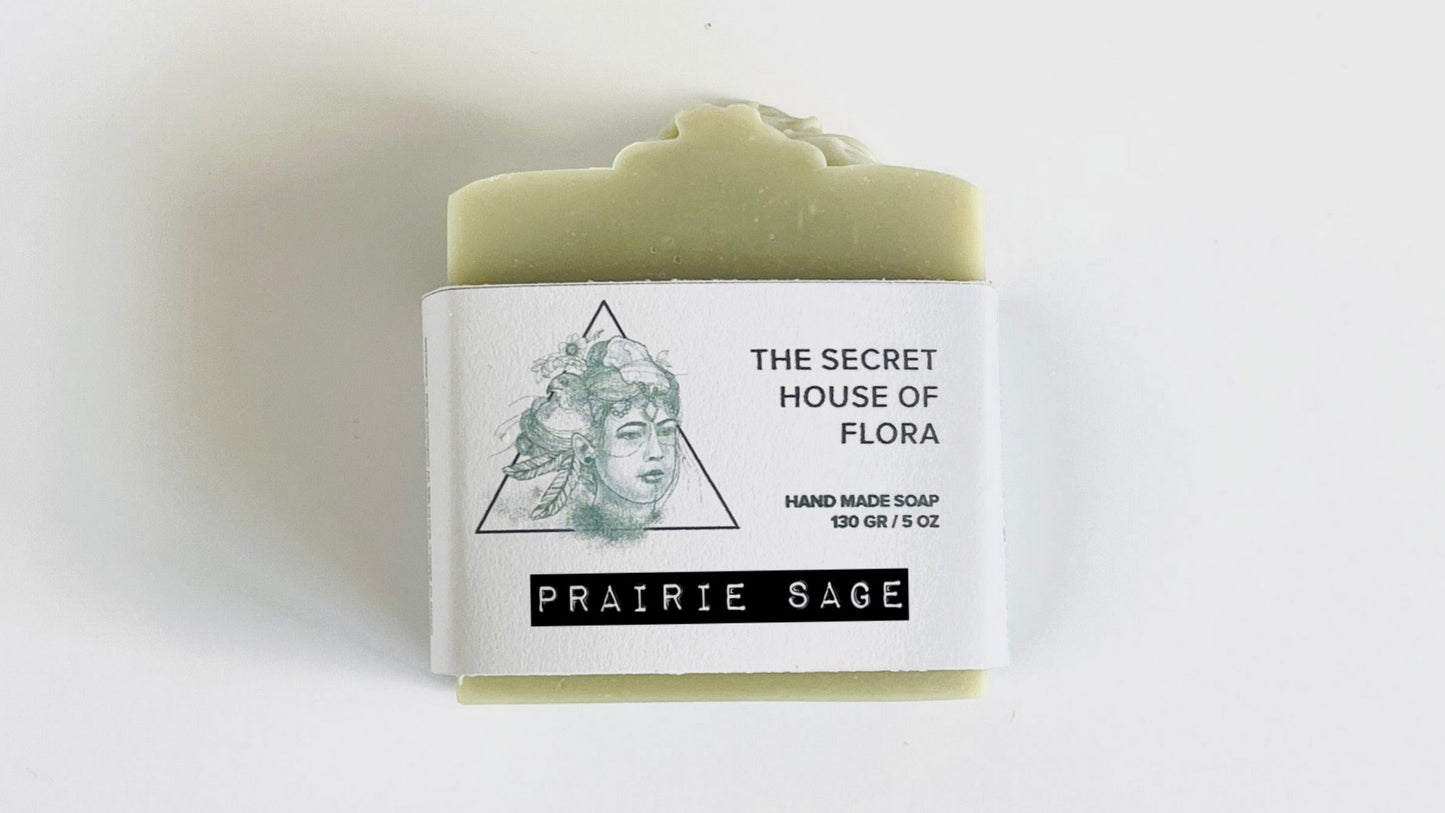 Bar of sage green soap with a label on a white background.