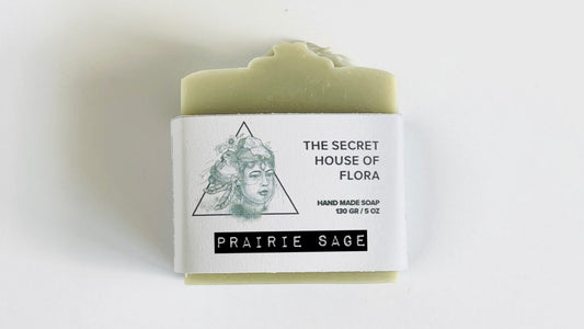 Bar of sage green soap with a label on a white background.