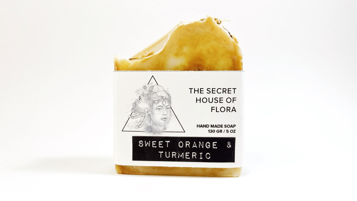 Bar of soap with beautiful orange and white swirls with packaging labeled 'The Secret House of Flora' on a white background.