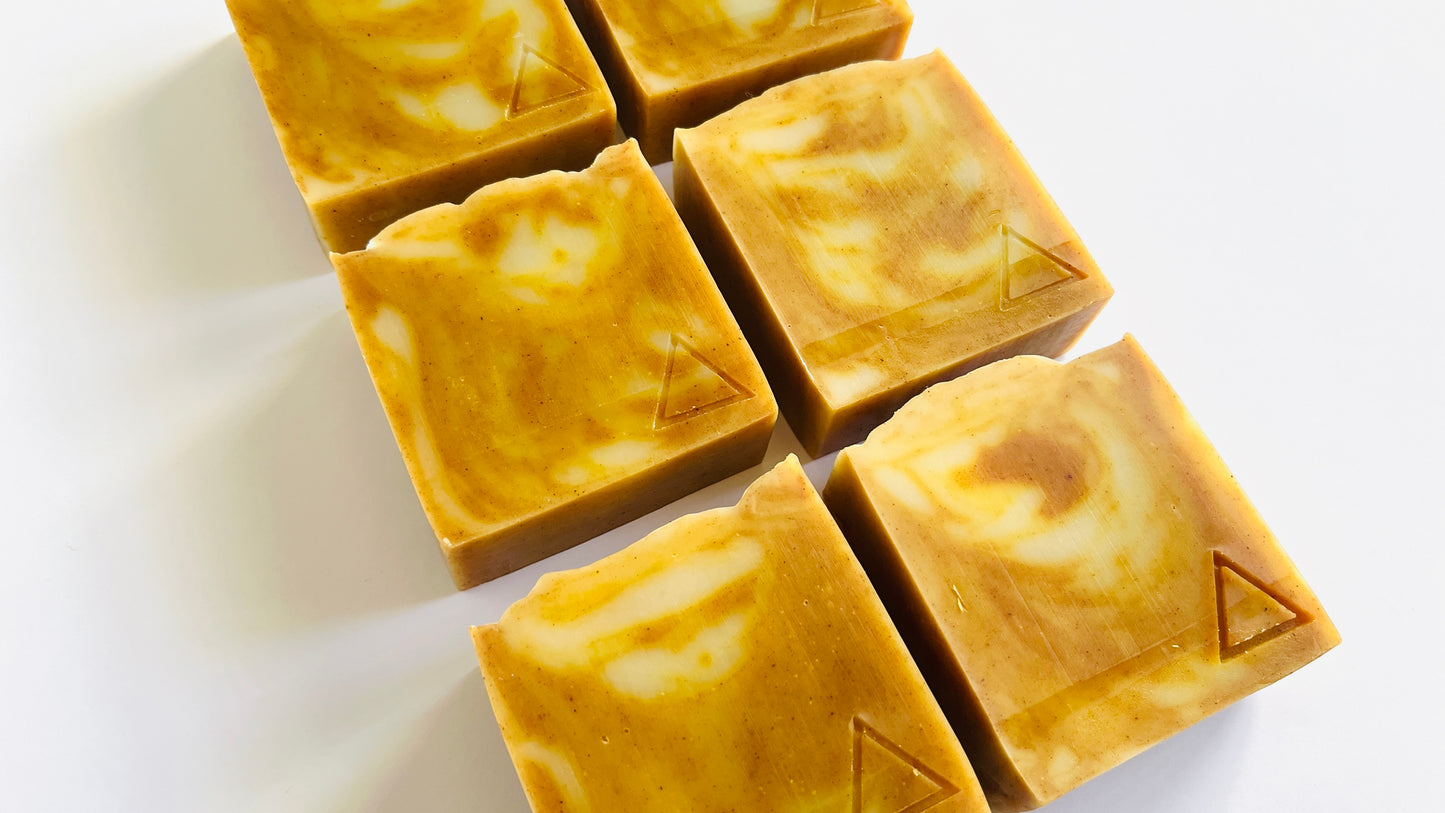Square bars of orange and white marbled soap on a white background. 