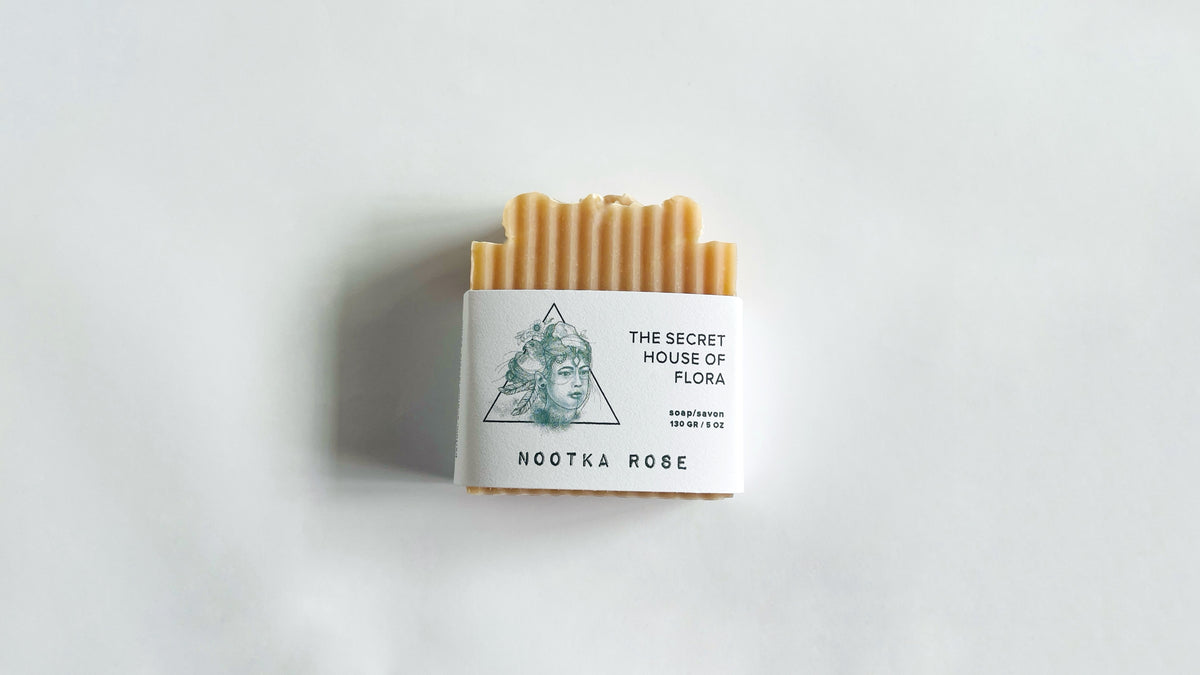 Bar of pink soap with packaging labeled 'The Secret House of Flora' on a light background